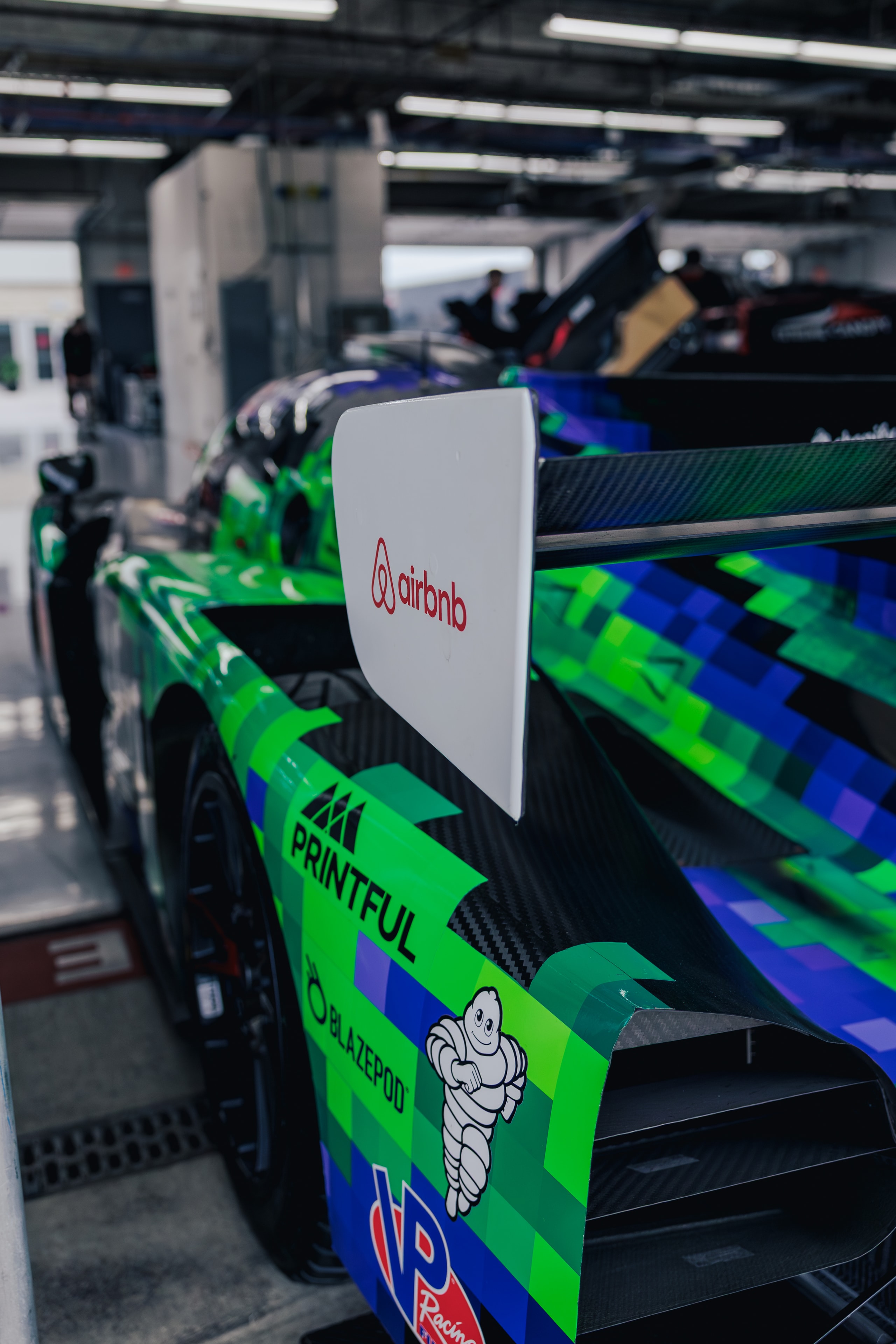 Brightly patterned race car in the garage with sponsor branding
