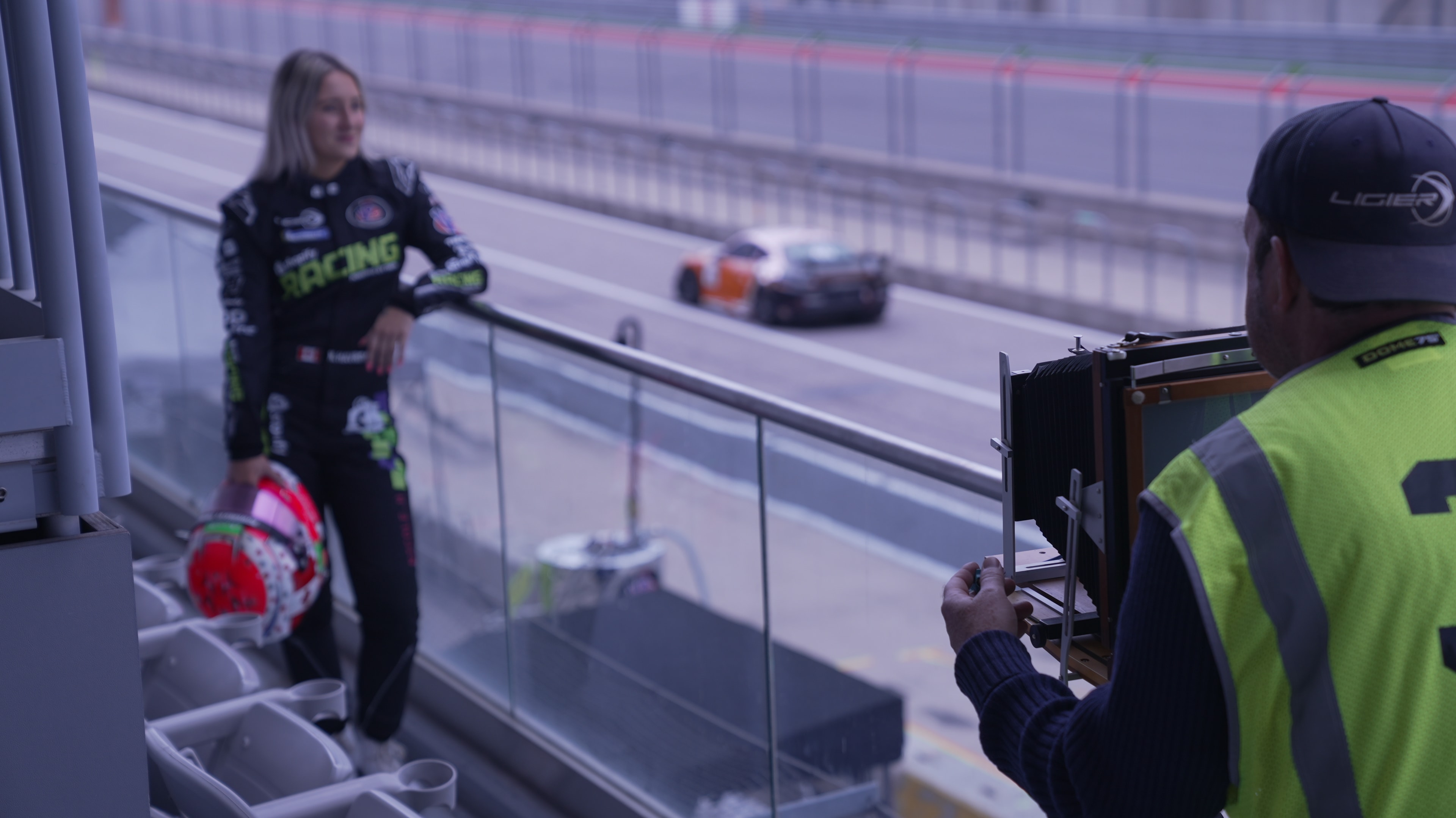 Race driver posing while a photographer captures content beside the pit lane