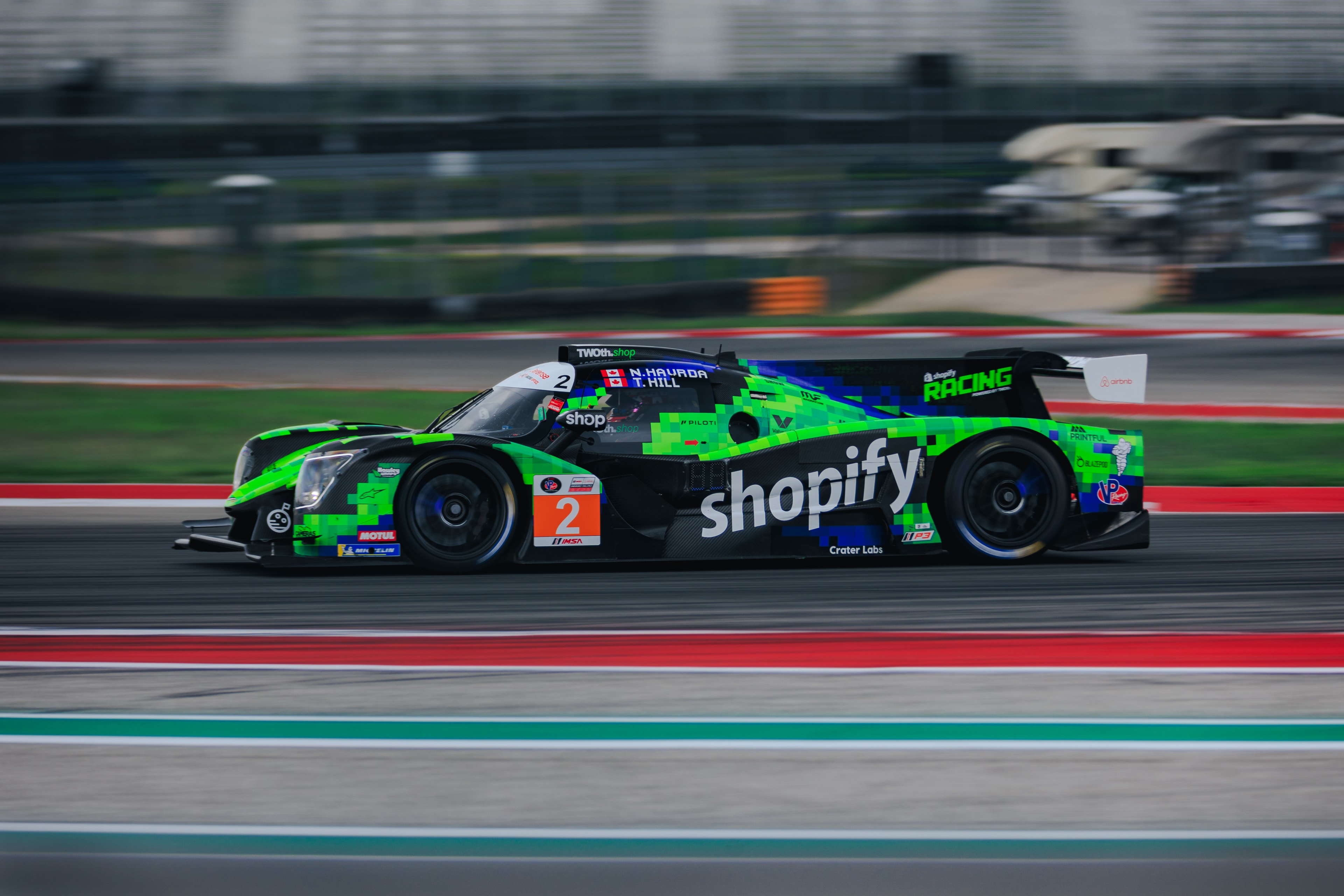 Shopify-branded race car in motion on the circuit