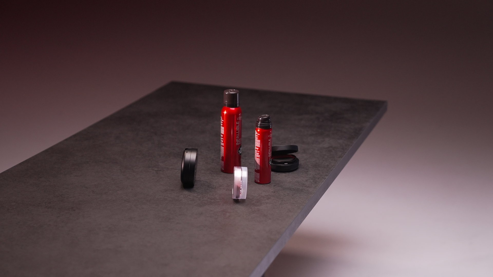 Red beauty products arranged on a dark studio table