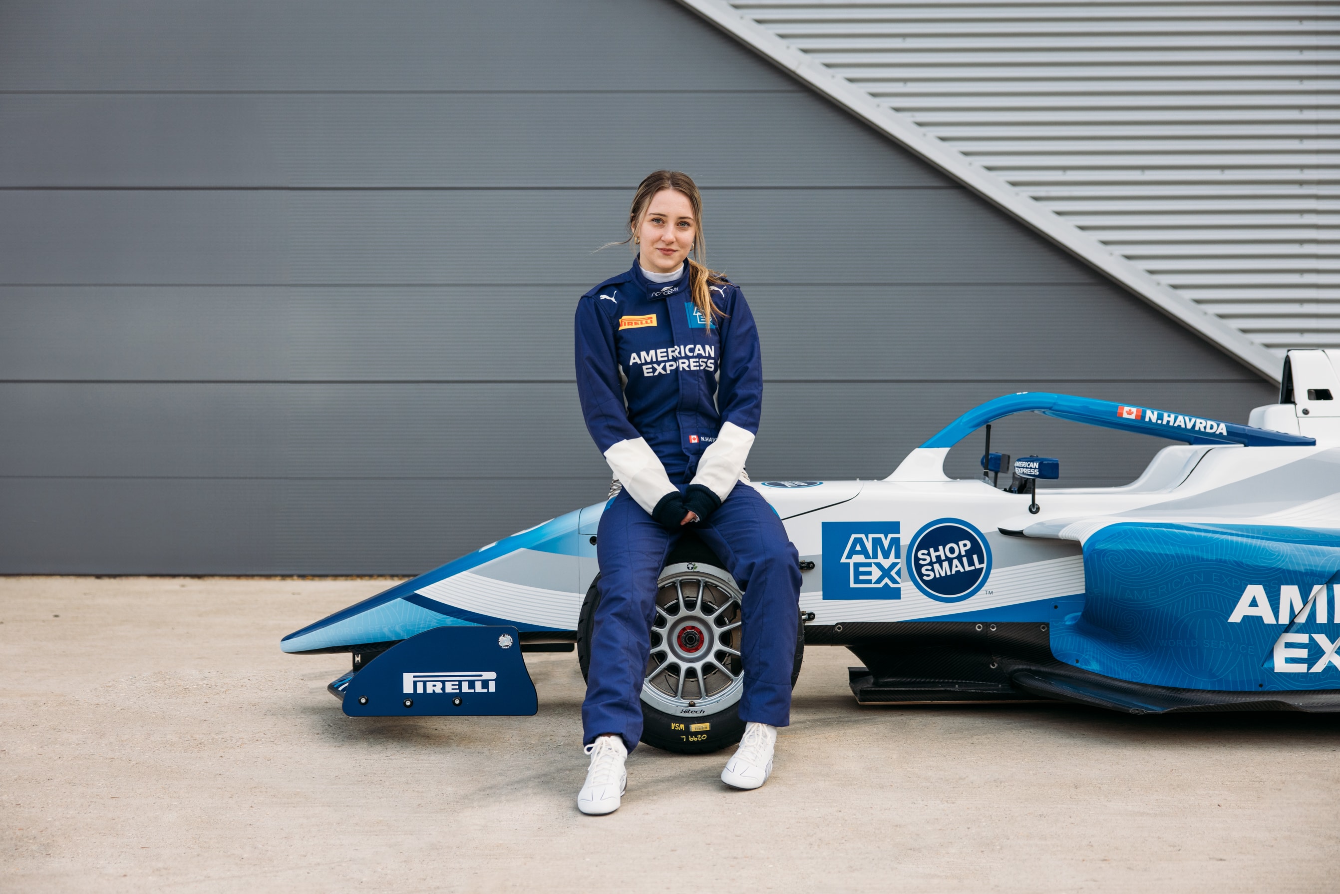 Nicole Havrda seated beside her American Express-branded race car
